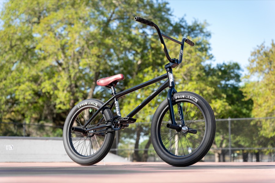 A black BMX bike on Alienation Prowler rims, parked on a sunlit skatepark deck.